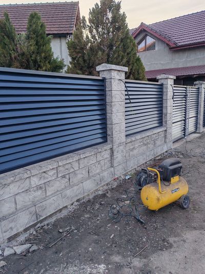 Poartă culisantă antracit lângă gard din beton gri