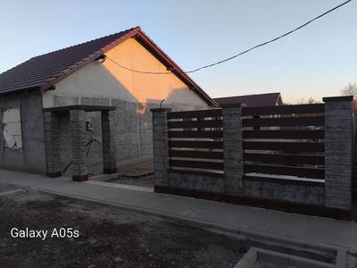 Gard din beton gri cu șipci maro și poartă, la apus