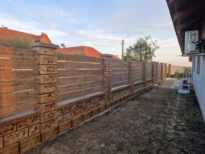 Gard din beton decorativ maro cu șipci metalice, pe toată lungimea curții