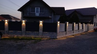 Gard din beton gri cu șipci antracit, curte în zi senină