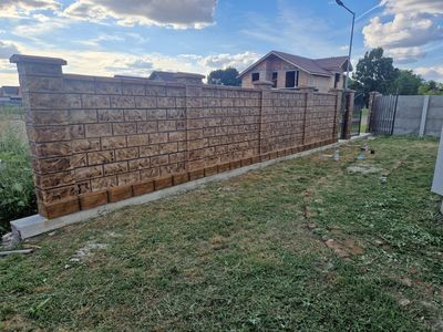 Gard din beton maro cu șipci, perspectivă lungă la asfințit