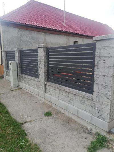 Detaliu de gard din beton gri cu șipci metalice